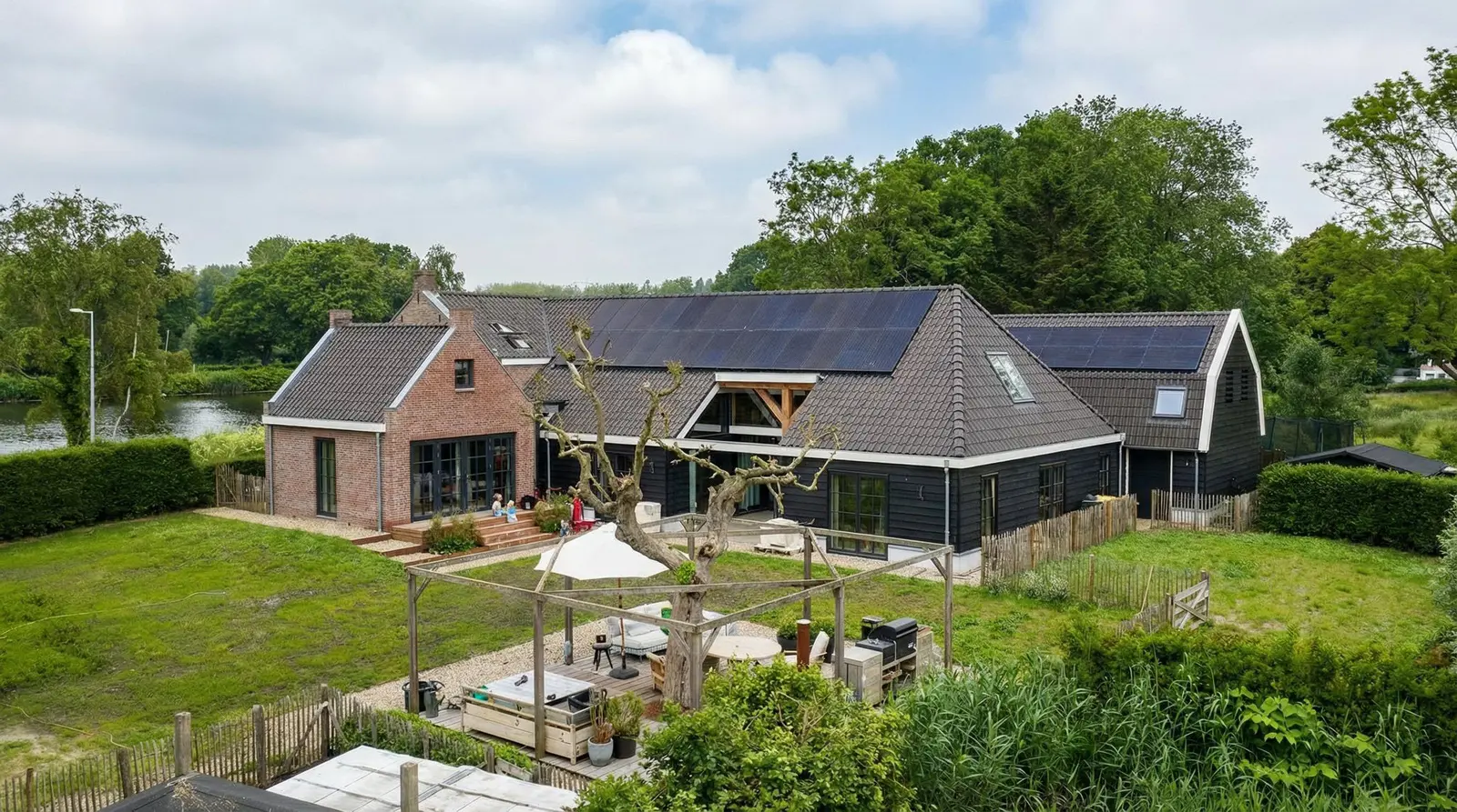 Het gerestaureerde boerderijensemble aan de Amstel, met zicht op het voorhuis en de nieuwgebouwde schuur.