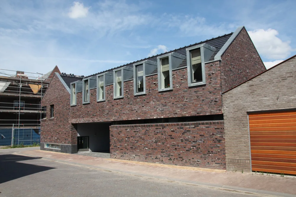 Ruwe baksteen met uitgemetselde vensterbanken en zinken dakkapellen bij hofwoning Cronenburgh