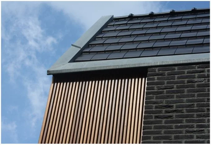 Koppeling volumes via doorlopende tuinmuur - woning en studio als één ensemble