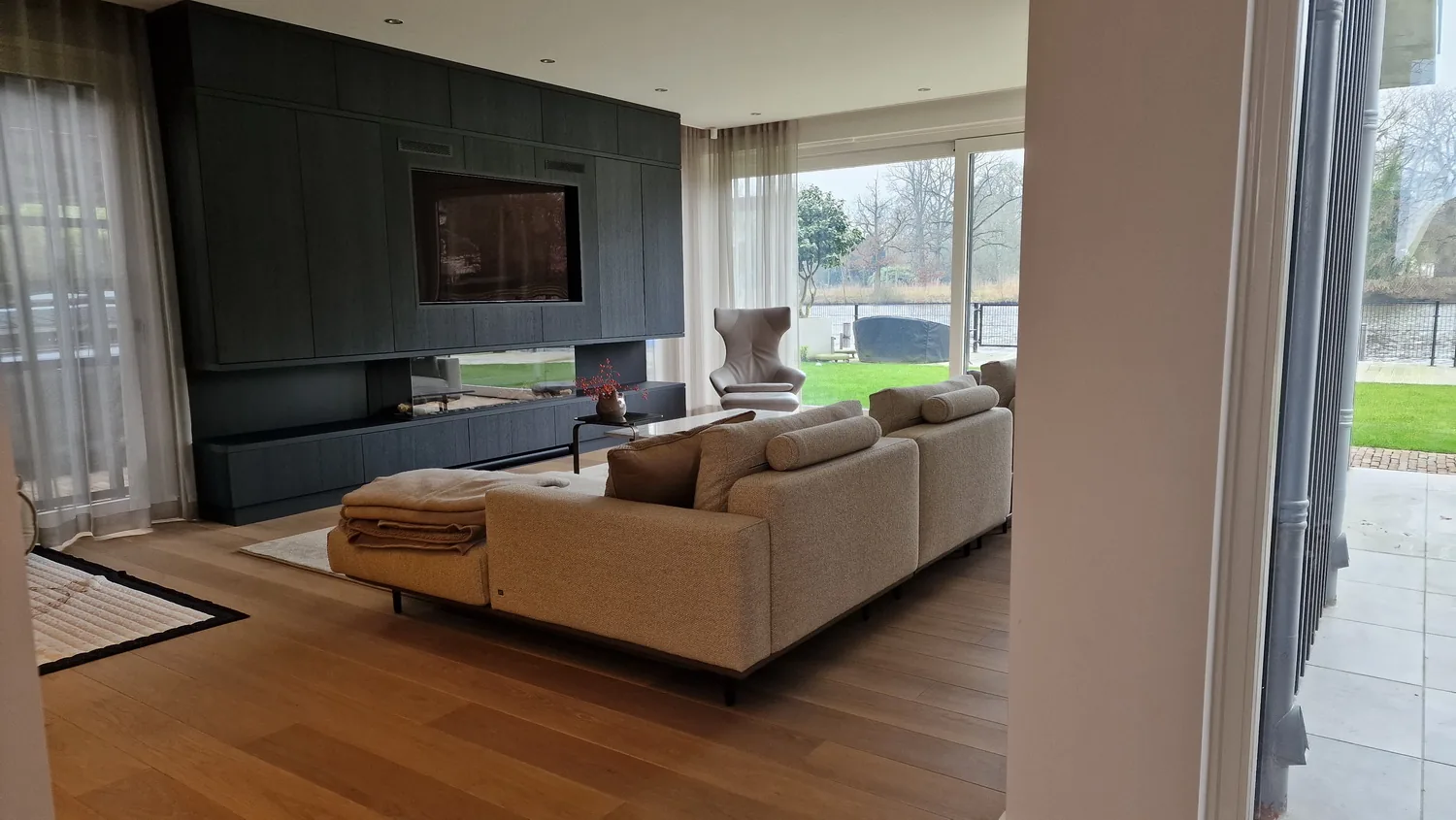Binnenzicht vanuit de uitbreiding met royale glasgevel: ruimtelijkheid en contact met de omgeving.