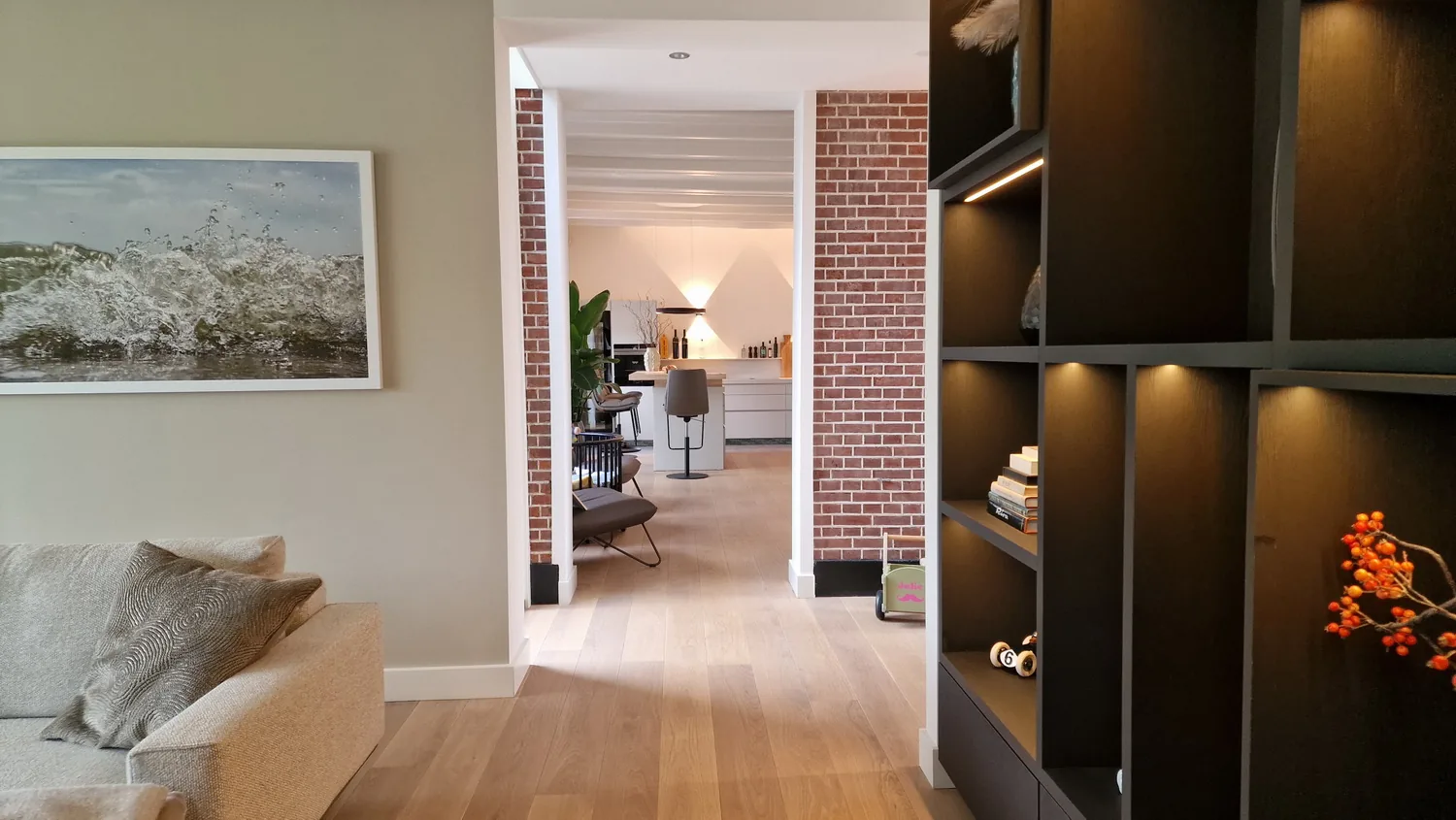 Woonzone met maatwerk kastenwand en lange zichtlijn, gericht op opbergen en orde.
