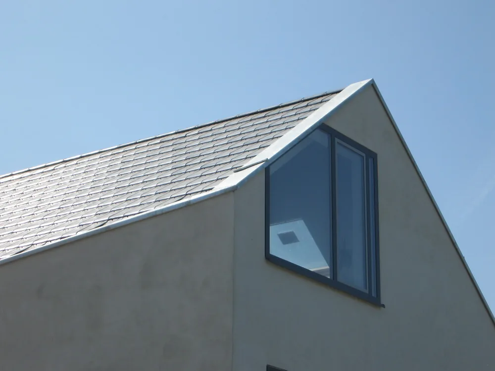 Gevel met keimwerk, leisteen plint en vlak liggende aluminium kozijnen