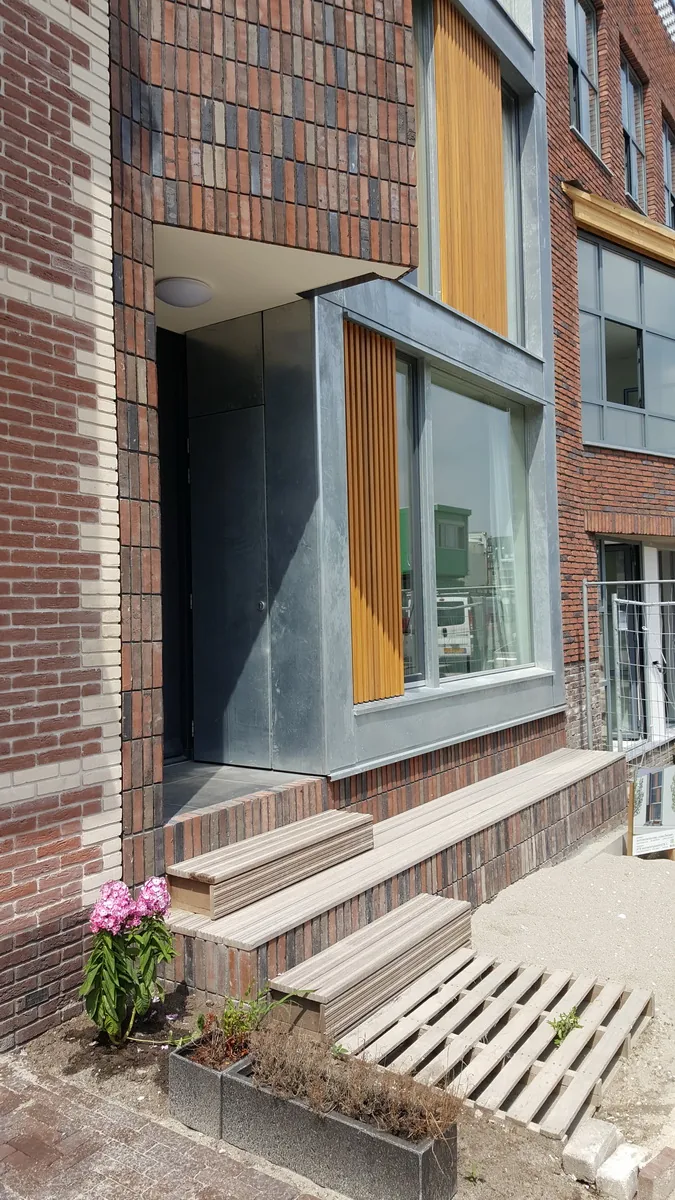 Materialisering: verticaal metselwerk, glas, zink en houten schermen