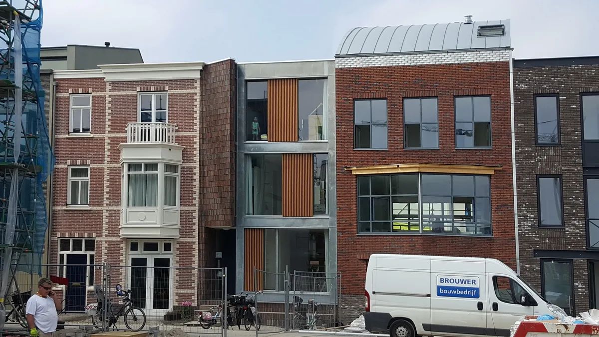 Stadswoning in Coendersbuurt Nieuw Delft met contrast tussen metselwerk, glas, zink en houten schermen
